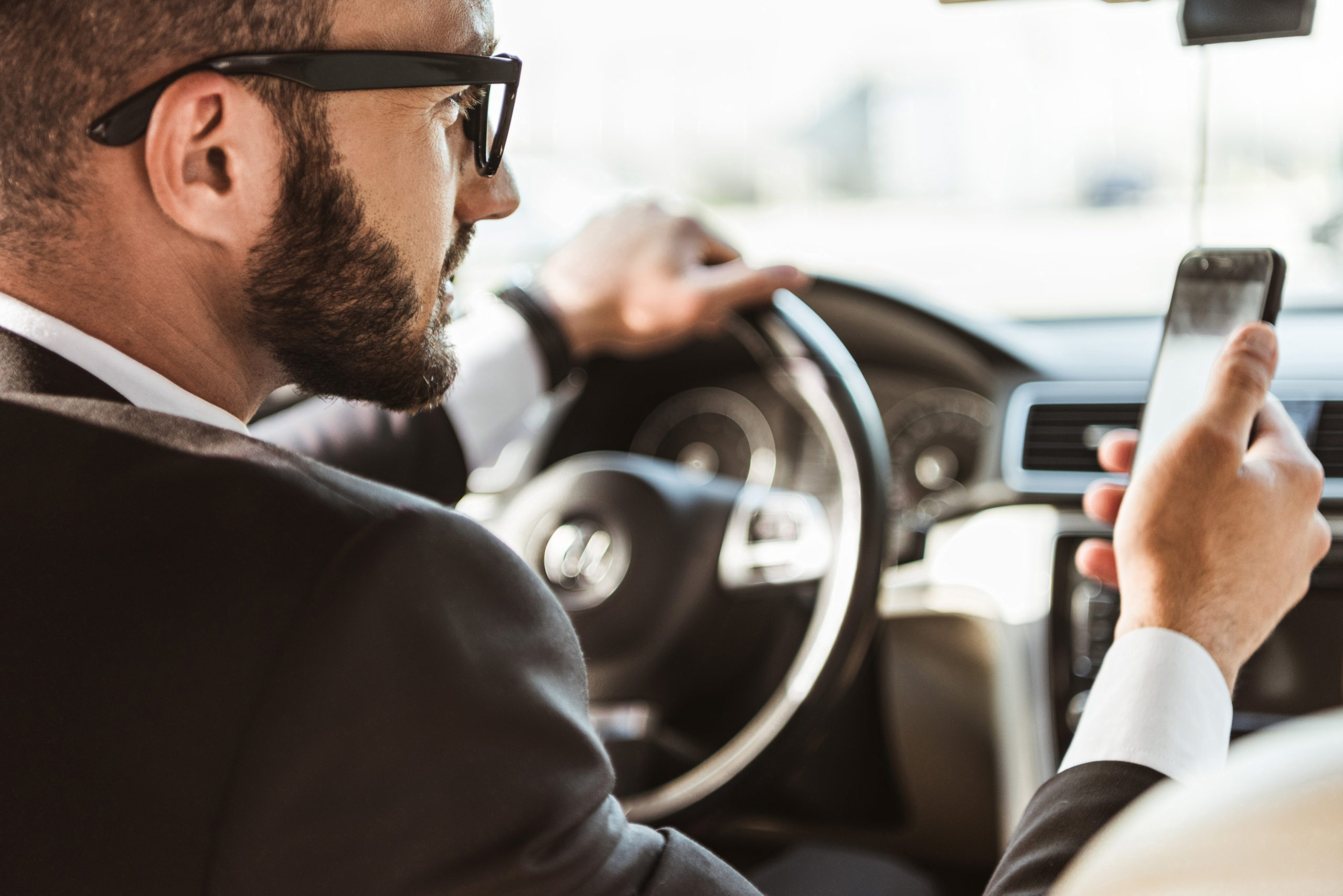 handsome driver in suit driving car and holding sm DMKMH8F scaled